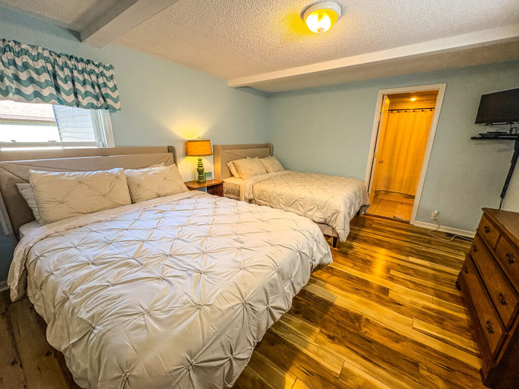 En queen-size-säng i ett delat dubbelrum med två queen-size-sängar och delat badrum